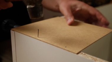 Dolabın arka duvarı çivi ve çekiçle çivilenmiş. Dolap mobilyalarının montajı.