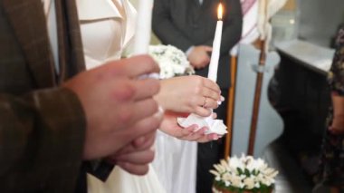 The bride and groom hold candles in the church during the wedding ceremony.