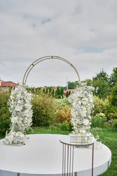 The welcoming arch is decorated with white flowers and roses. Wedding celebration ceremony.