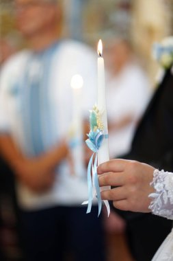 The bride and groom hold candles in the church during the wedding ceremony.                            