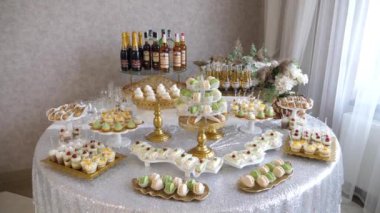 Açık büfe masasının rafına çeşitli alkollü içecekler, tatlı kekler ve hamur işleri serilmiştir. Açık büfe masasının dekorasyonu. Ukrayna. Lviv (7.10.23)