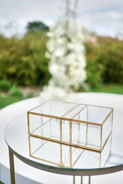 There is a transparent box for greeting cards on the table near the greeting arch. Wedding ceremony.