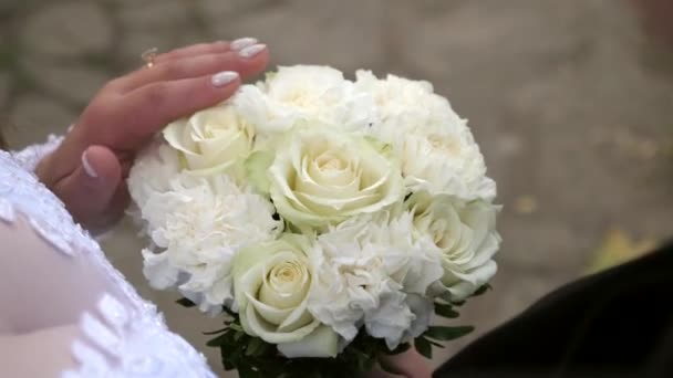 La mariée touche doucement les fleurs du bouquet. Amour et relations romantiques.