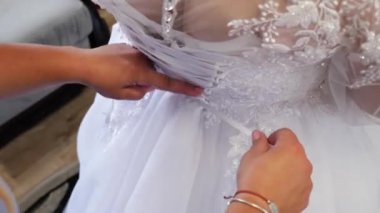 Gelinin bir arkadaşı gelinliğini giymesine yardım etmek için arkadan bağcıkları bağlıyor. Düğün hazırlıkları..