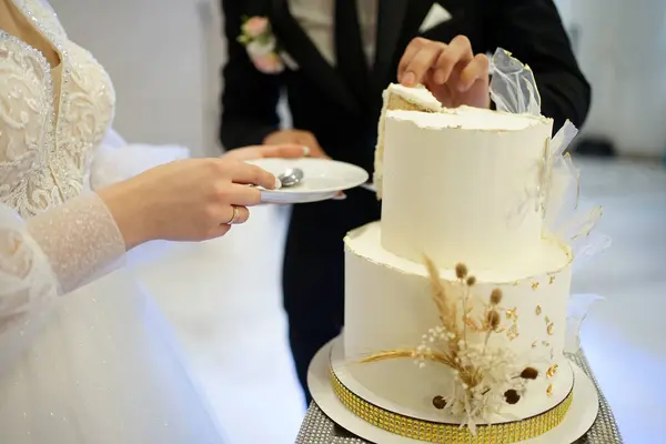 The newlyweds cut a piece of the wedding cake. Traditions of wedding celebration.