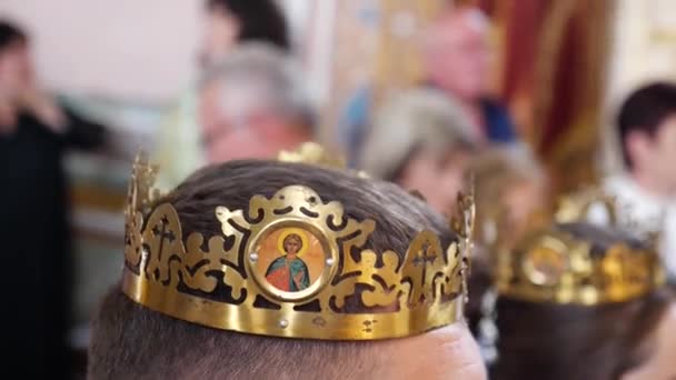 教会の結婚式では 結婚式の王冠は新婚者の頭の上に置かれます — ストック動画