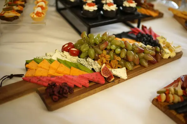 Buffet table with cheese, grapes and sweets.