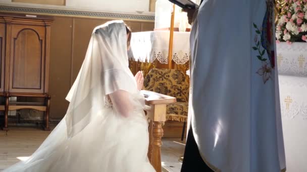 在教堂的仪式上 新娘跪在圣像前祈祷 — 图库视频影像