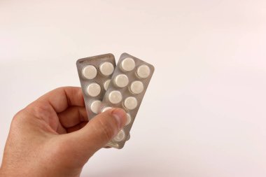 Bir adam elinde grip ve soğuk algınlığı hapları tutuyor. Akut solunum hastalıklarının tedavisi.