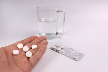 Bir adam elinde grip ve soğuk algınlığı hapları tutuyor. Akut solunum hastalıklarının tedavisi.