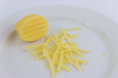 Minyatür bir rende ve beyaz bir tabakta rendelenmiş patates..