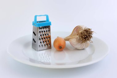 Beyaz bir tabakta elle rendelenmiş soğan ve sarımsak..