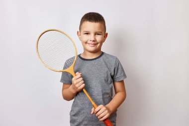 Gülümseyen bir çocuk elinde bir badminton raketi tutuyor. Spor ve beden eğitimi.