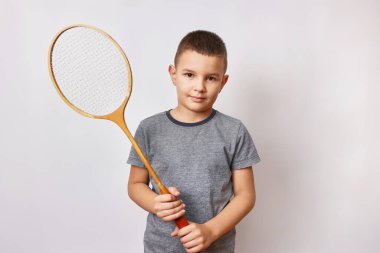 Gülümseyen bir çocuk elinde bir badminton raketi tutuyor. Spor ve beden eğitimi.