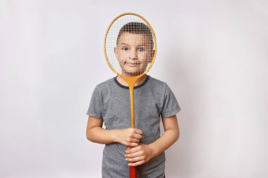 Gülümseyen bir çocuk elinde bir badminton raketi tutuyor. Spor ve beden eğitimi.