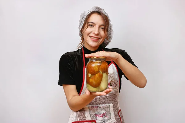 A beautiful girl holds homemade jam in her hands. Housework concept.