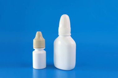 Mavi arka planda sıvı haldeki iki ilaç şişesi..