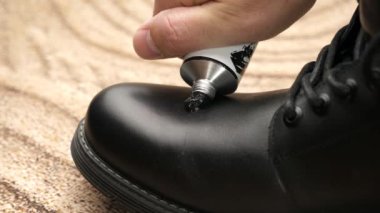 Siyah deri botlar ayakkabı kremiyle temizlenir. Ayakkabı bakımı kavramı.
