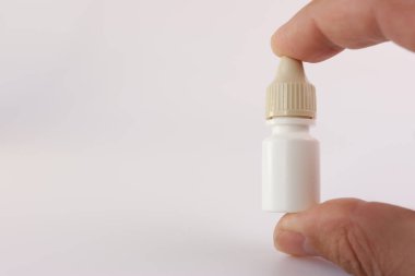 Bir adam beyaz bir arka planda elinde bir ilaç şişesi tutuyor..