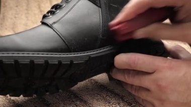 Siyah deri botlar ayakkabı kremiyle temizlenir. Ayakkabı bakımı kavramı.