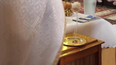 Bir kilise düğünü sırasında rahip alyanslara kutsal su serper. Kilise düğün gelenekleri.