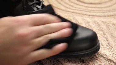 Siyah deri botlar yün bir bezle çamurdan temizlenir. Ayakkabı bakımı kavramı.