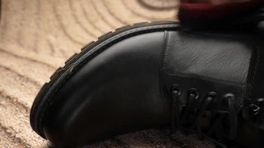Siyah deri botlar bir fırçayla çamurdan temizlenir. Ayakkabı bakımı kavramı.