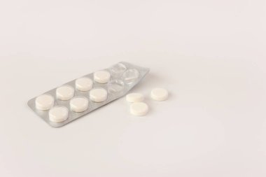 Beyaz arka planda bir paket beyaz hap. İlaç ve sağlık hizmetleri.