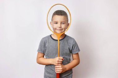 Gülümseyen bir çocuk elinde bir badminton raketi tutuyor. Spor ve beden eğitimi.