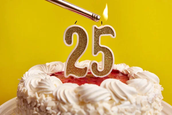 A candle in the form of the number 25, stuck in a festive cake, is lit. Celebrating a birthday or a landmark event. The climax of the celebration.