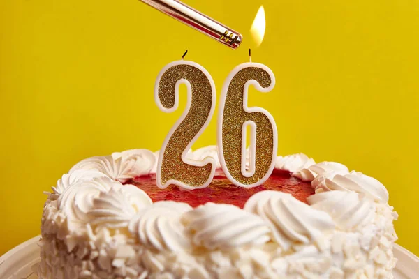 A candle in the form of the number 26, stuck in a festive cake, is lit. Celebrating a birthday or a landmark event. The climax of the celebration.