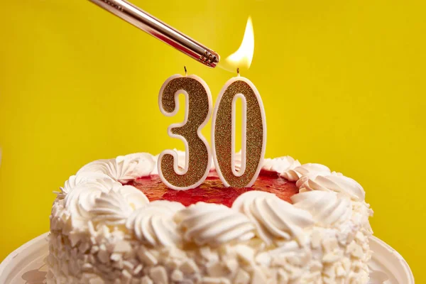 A candle in the form of the number 30, stuck in a festive cake, is lit. Celebrating a birthday or a landmark event. The climax of the celebration.
