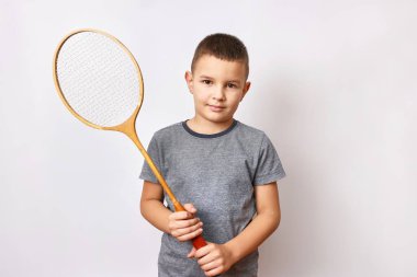 Gülümseyen bir çocuk elinde bir badminton raketi tutuyor. Spor ve beden eğitimi.