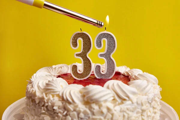A candle in the form of the number 33, stuck in a holiday cake, is lit. Celebrating a birthday or a landmark event. The climax of the celebration.
