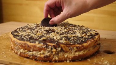 Pastayı çikolata ve fındıkla süslüyorsun. Evde şenlikli turta pişiriyorum. Yavaş çekim.