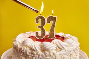 37 numaralı pasta şeklinde bir mum, şenlikli bir pastaya sıkıştı ve yakıldı. Bir doğum gününü ya da tarihi bir olayı kutluyoruz. Kutlamanın doruk noktası..