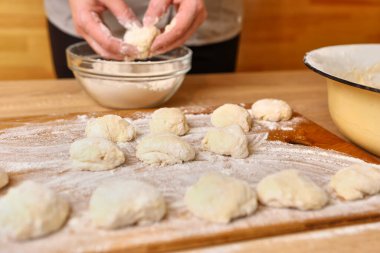 Bir kadın çörek yapmak için hamur parçaları oluşturur. Çörek yapma süreci.