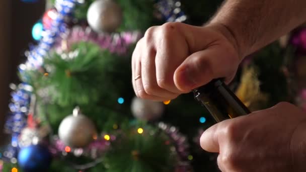 Фоне Рождественской Елки Гирляндами Откупоривается Бутылка Шампанского — стоковое видео