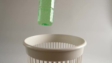 Plastik bir su şişesi geri dönüşüm için çöpe atılır. Yavaş çekim.