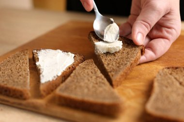 Kanepe hazırlamak için, ekşi süt peynirini kahverengi ekmeğe sürün.