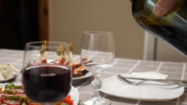 Kırmızı şarap, şenlik yemekleriyle dolu bir masada bir bardağa doldurulur.