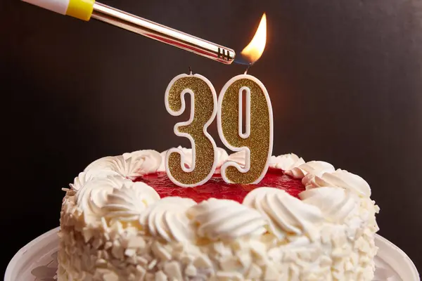 A candle in the form of the number 39, stuck in a festive cake, is lit. Celebrating a birthday or a landmark event. The climax of the celebration.