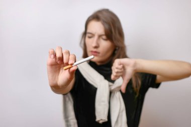 Kız elinde bir sigara tutuyor ve parmağını aşağı işaret ediyor. Sigara içmenin kötü alışkanlığı..