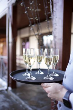 Şampanya dolu bardaklar bir tepside tutulur..