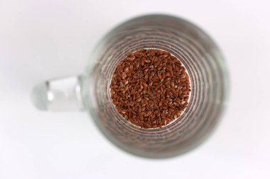 Bir decoction hazırlamak için keten tohumları bir bardağa dökülür. Flax 'in tıbbi özellikleri.