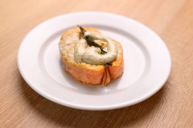 Beyaz bir tabakta taze pişmiş somon bifteği ve sos..