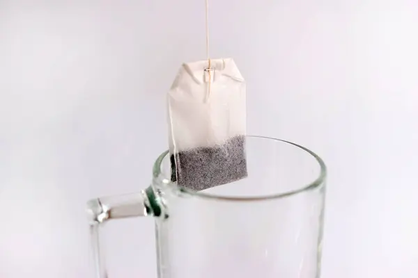 A tea bag is dropped into the glass. Preparation of fragrant tea.