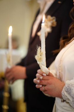 Yeni evliler bir kilise düğününde ellerinde yanan mumlar tutarlar..                               