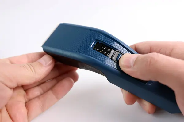 A man gets acquainted with the functions and capabilities of a hair clipper.