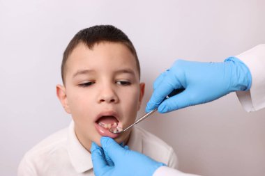 Bebek dişleri olmayan bir çocuğun ağız boşluğu diş aynası kullanılarak inceleniyor. Diş sağlığı ve diş bakımı.
